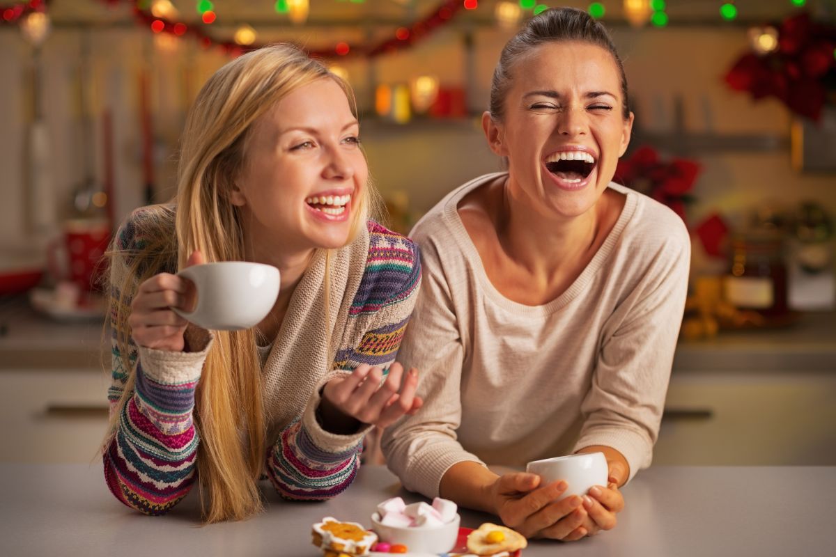 Are Christmas Cookies Bad for Your Teeth Couple laughing together holding mugs in festive holiday decorated home setting.