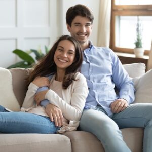 Smiling woman and man hugging, sitting on a cozy couch in dental Office. 