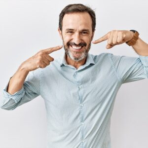 Middle age hispanic man with beard standing over isolated background smiling cheerful showing and pointing with fingers teeth and mouth.