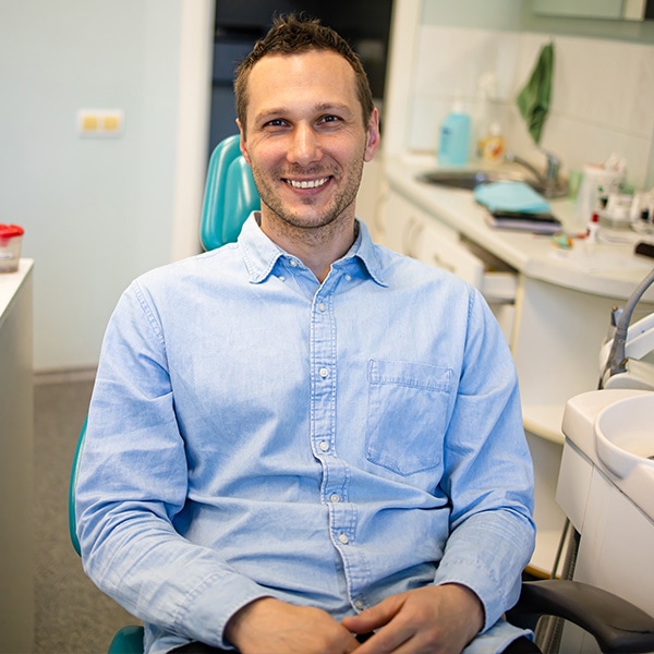 Cheerful man smiling towards sitting in a dental chair waiting for a dental examination.
