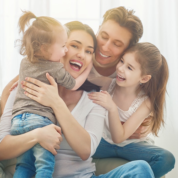 st-andrews-dental-center-panama-city-fl-services-kid-friendly-dentistry Mum, dad and girls laughing and hugging.
