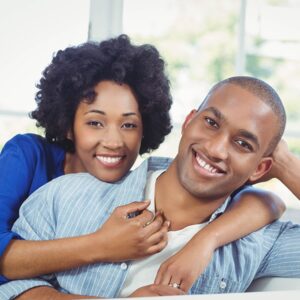 Happy smiling black couple sitting on a sofa.