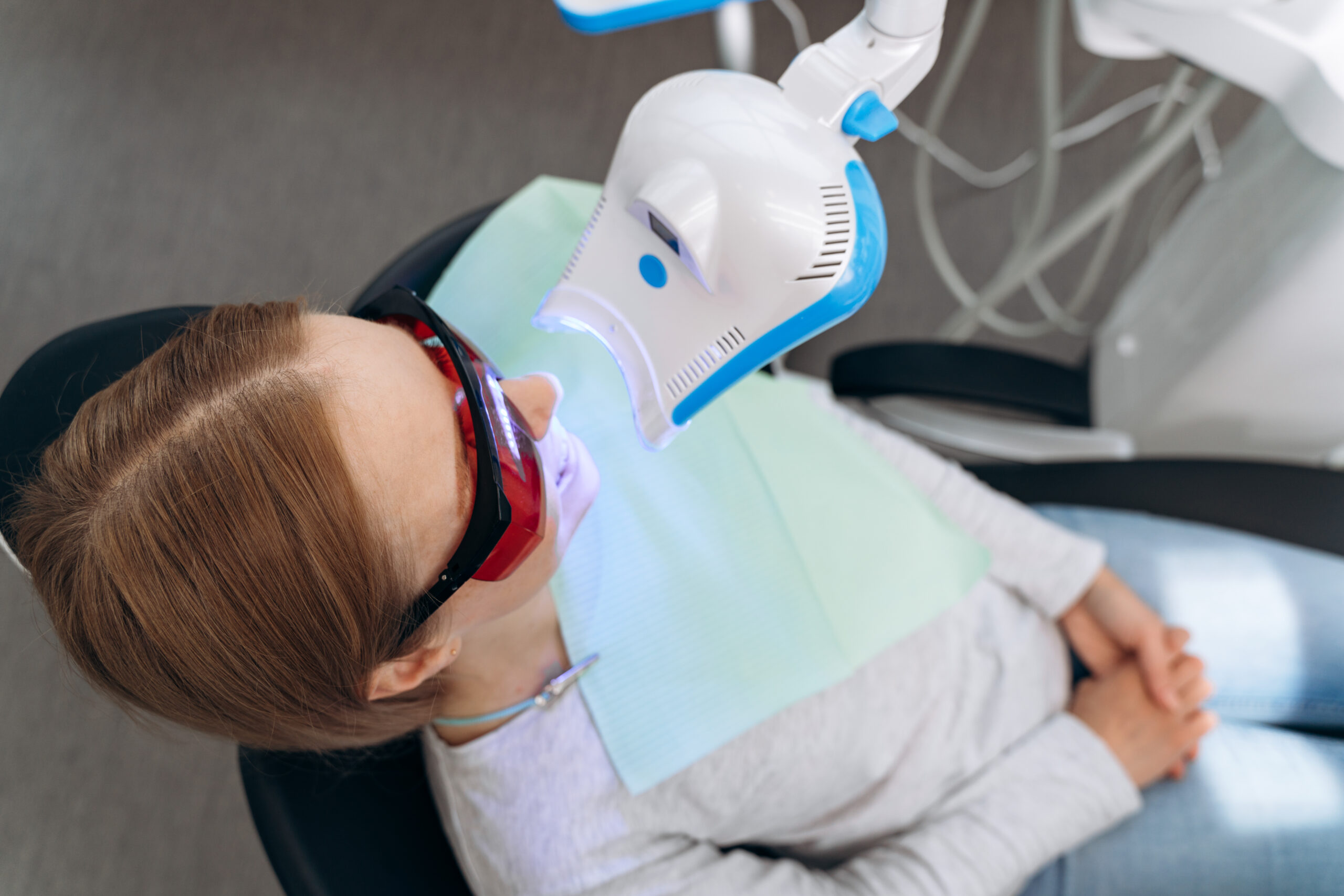 Attractive woman in a dental chair with goggles on a visit to the dentist. Work equipment shines on the patient’s teeth dentist in Panama City