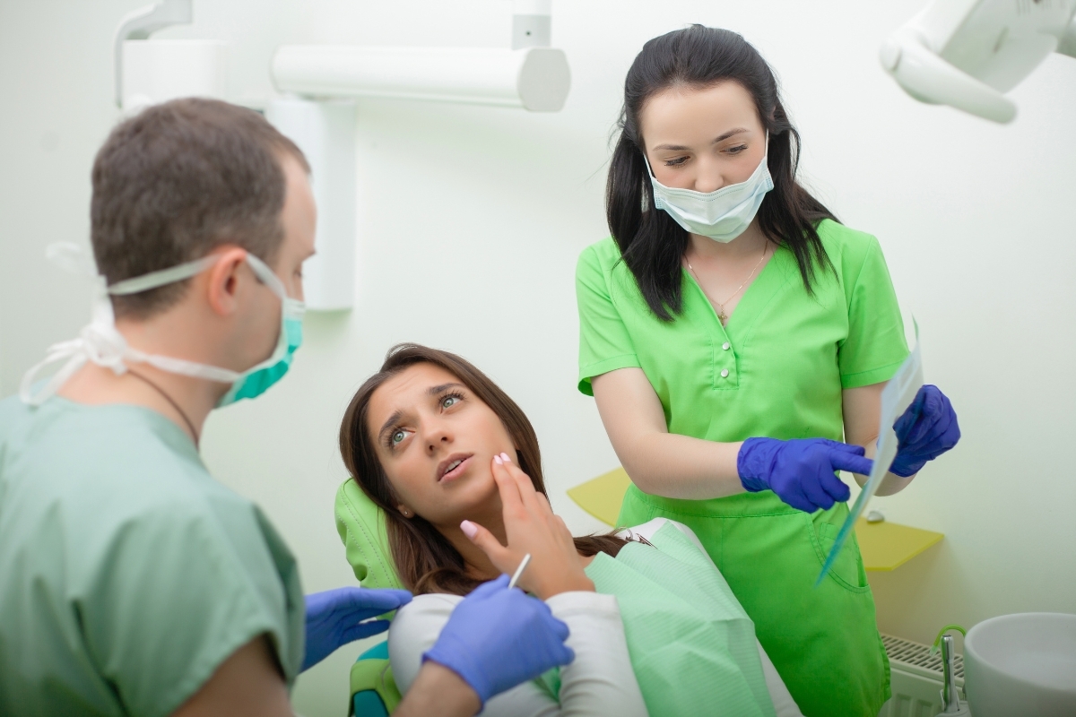 chipped tooth repair Dentist and dental assistant examining patient's tooth in treatment room for cracked tooth evaluation.